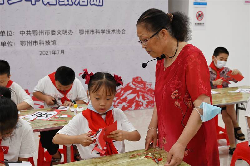 2021年7月10日，鄂州市科協(xié)組織落駕坪小學(xué)學(xué)生在鄂州市科技館開展社會主義核心價值觀系列活動，圖為開展的紅色剪影圓夢中華剪紙活動，老師指導(dǎo)同學(xué)剪紙.jpg